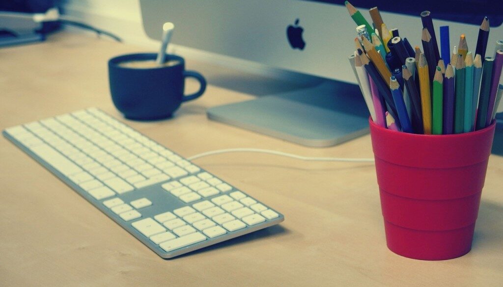 scrivania con pc, matite e tazza di caffè