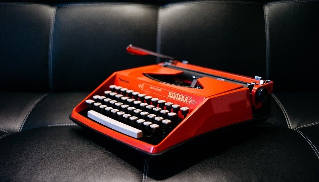 macchina da scrivere rossa su divano in pelle nera
