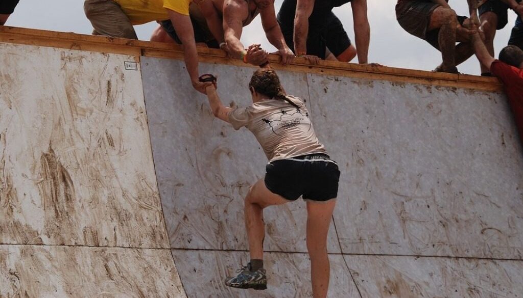 ragazza che supera un ostacolo con braccia che l'aiutano