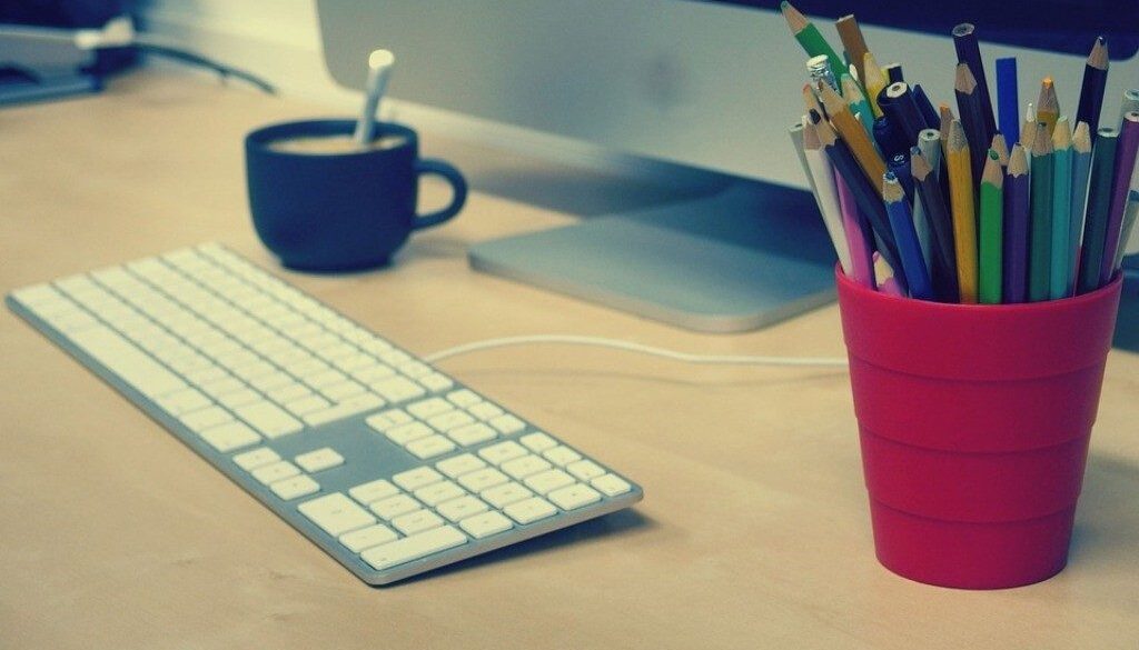 scrivania con pc, tazza, portapenne