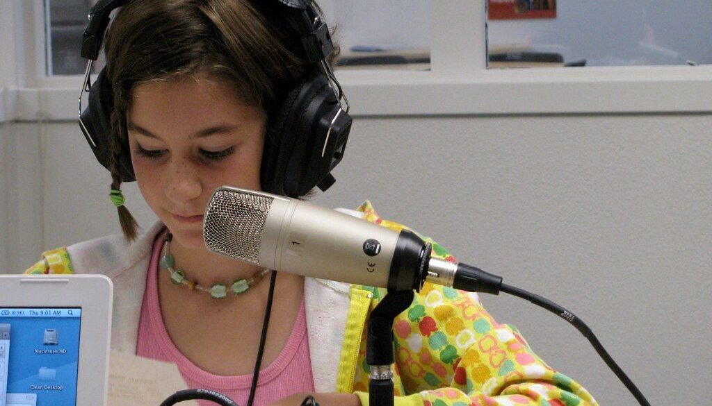 Elementary student being recorded with a microphone as part of a student produced podcast