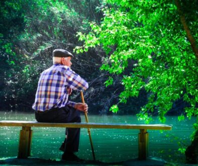 anziano seduto su una panchina davanti a un laghetto