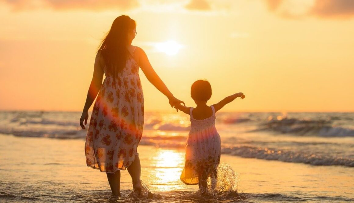 mamma e bambina su una spiaggia al tramonto