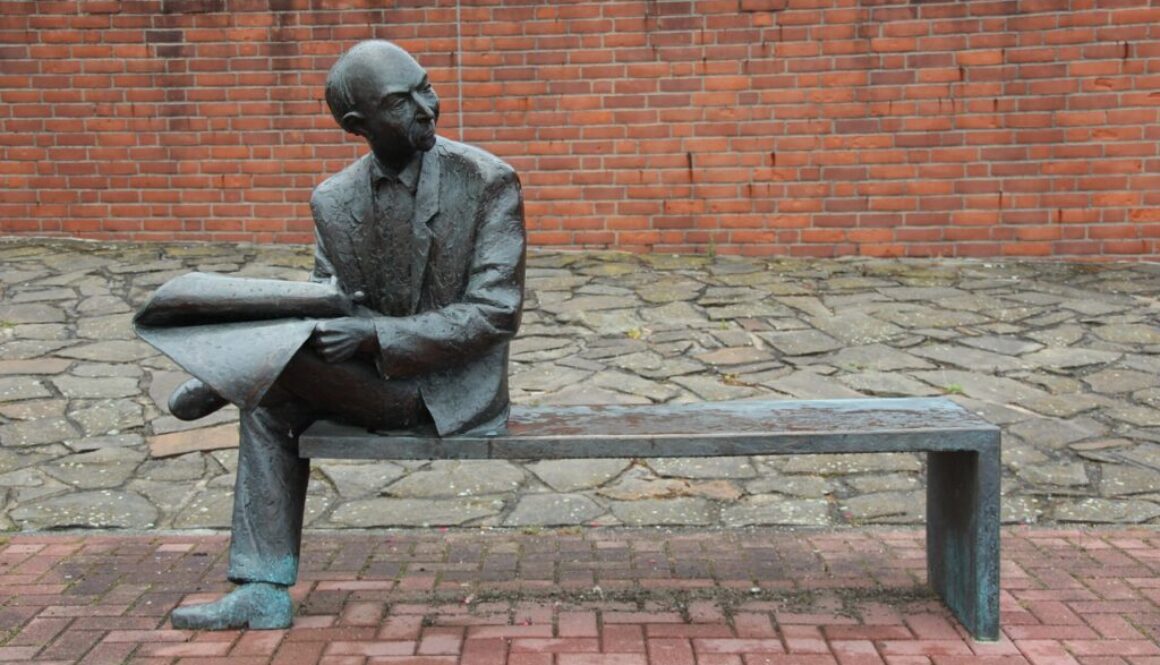 scultura uomo che legge su una panchina