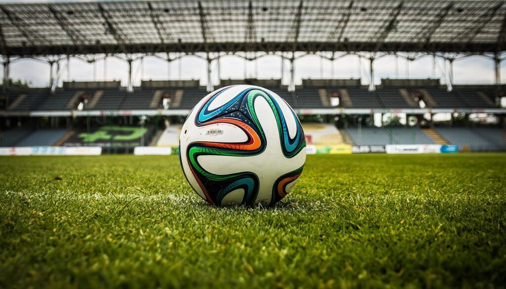 pallone da calcio fermo su campo da calcio con sfondo dello stadio