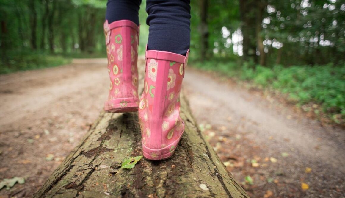 piedi di ragazza con stivali di gomma rosa che cammina nel bosco