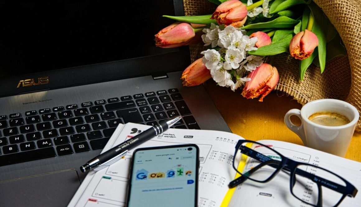 scrivania con pc, smarphone, agenda, mazzo di tulipani