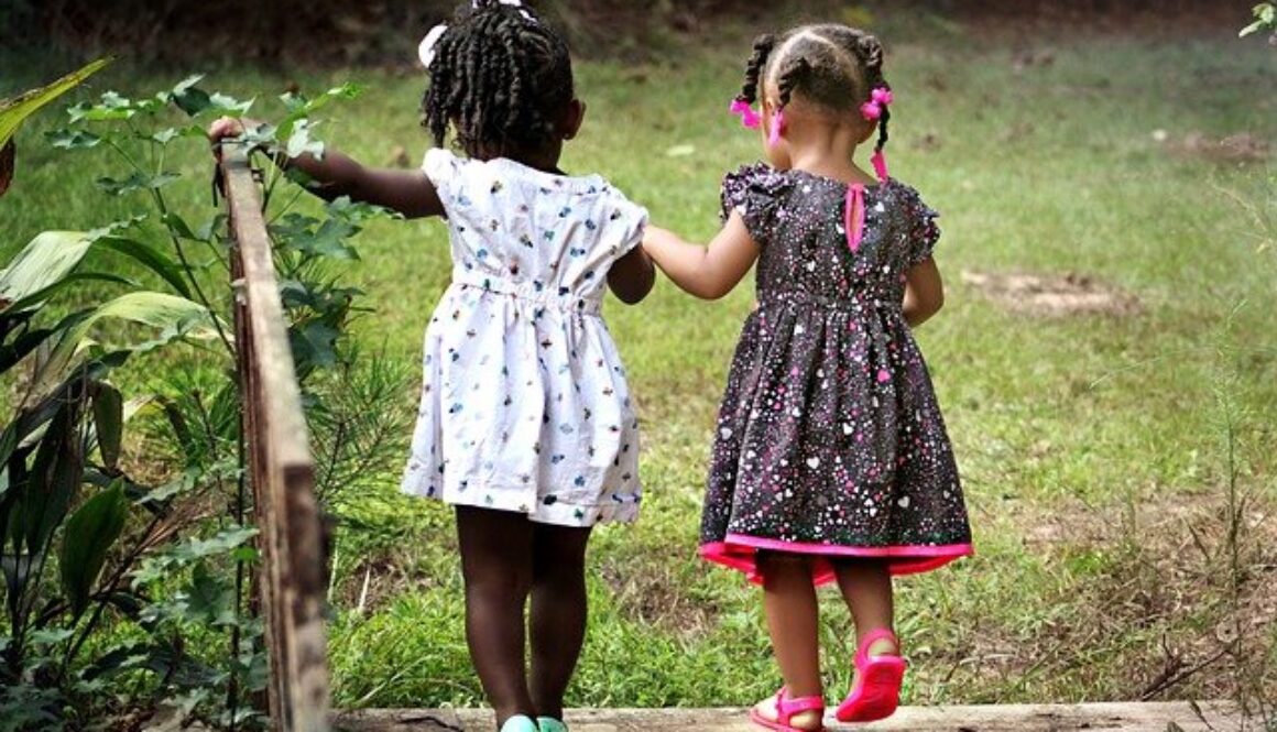due bambine di spalle che si tengono per mano camminando