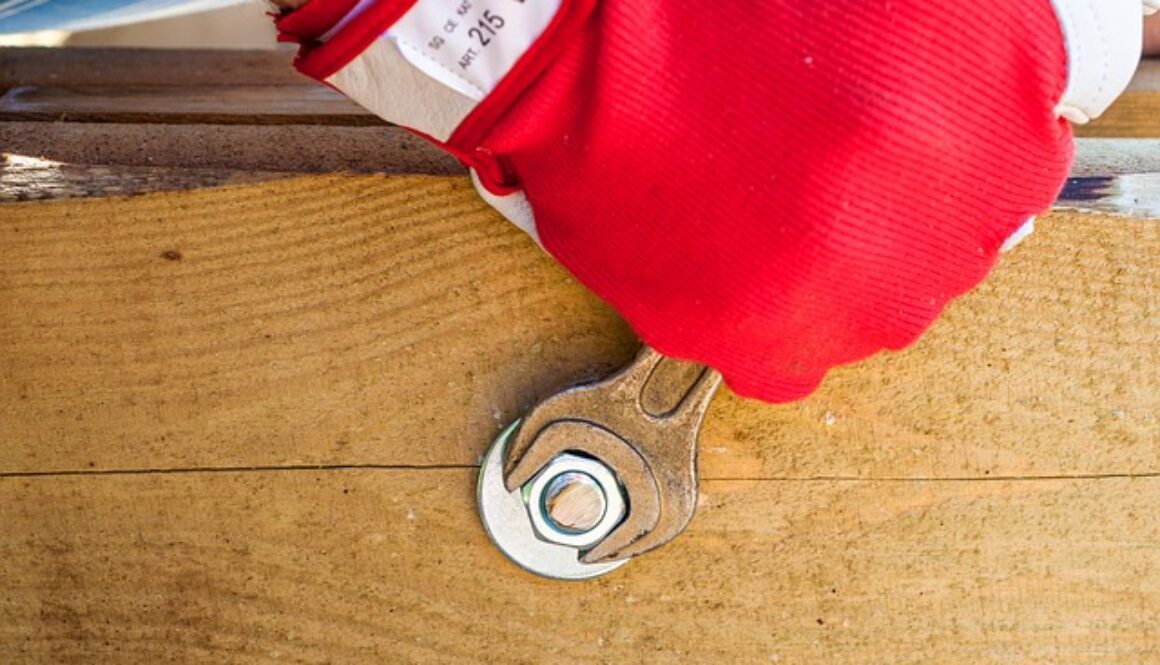 mano con guanto da lavoro rosso e chiave inglese