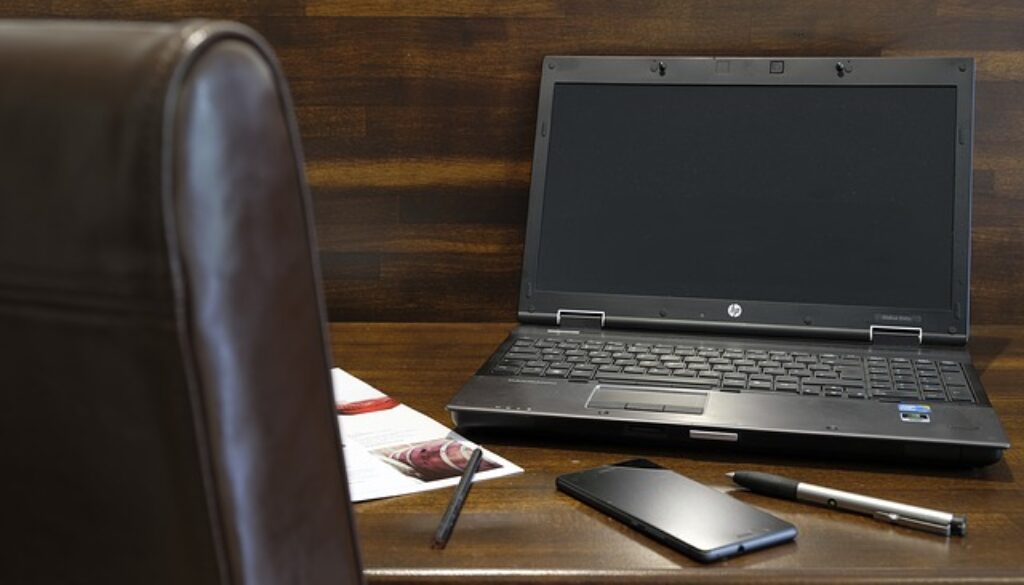 scrivania con sedia, computer, telefono, penne