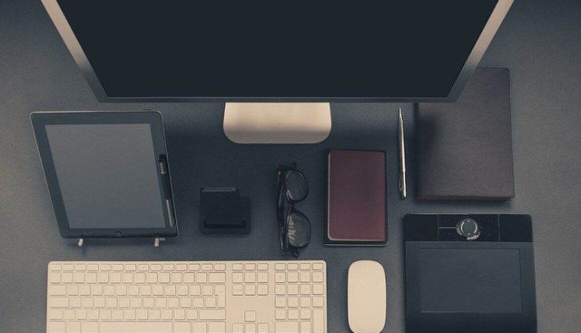 scrivania ufficio con schermo, tastiera, occhiali, agenda