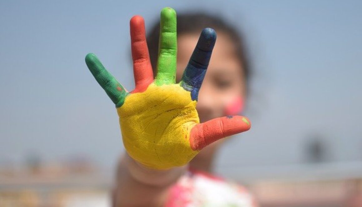 mano di un bambino con le cinque dita colorate. Di cosa si occupa l'esperto in cooperazione internazionale?