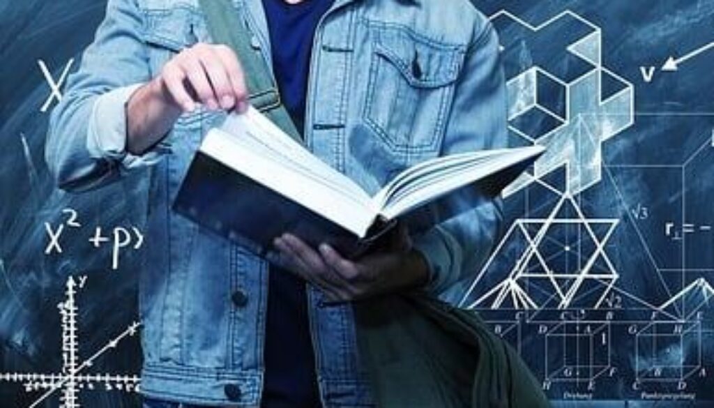 studente con libro davanti a lavagna con formule matematiche