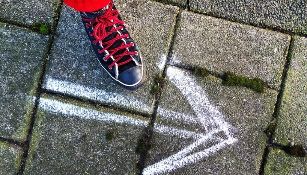 sneaker su asfalto con freccia bianca