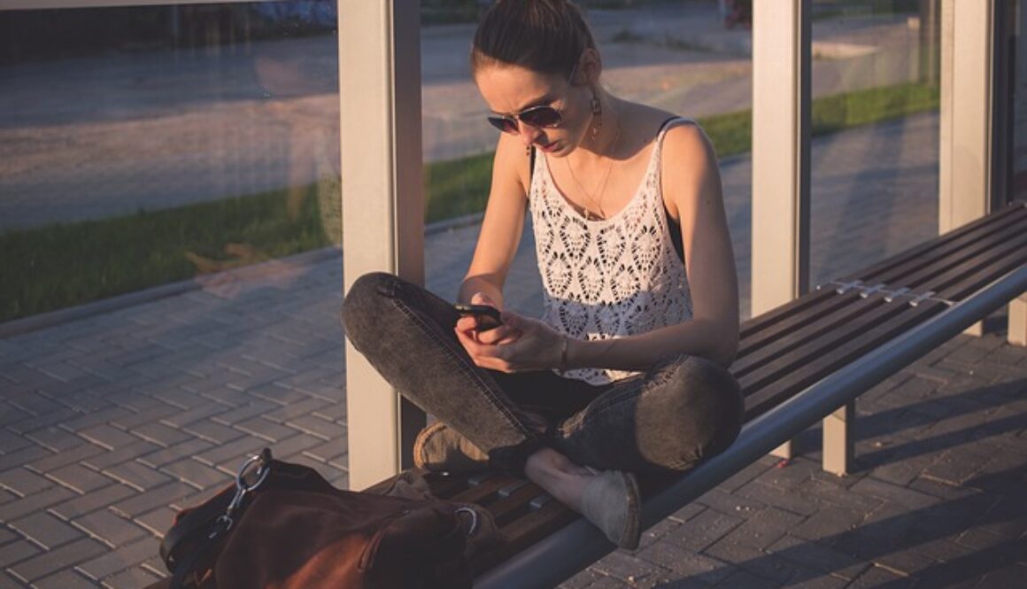 ragazza legge telefono alla fermata del bus