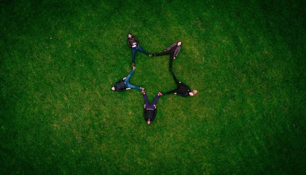 ragazzi sdraiati su un prato a formare una stella