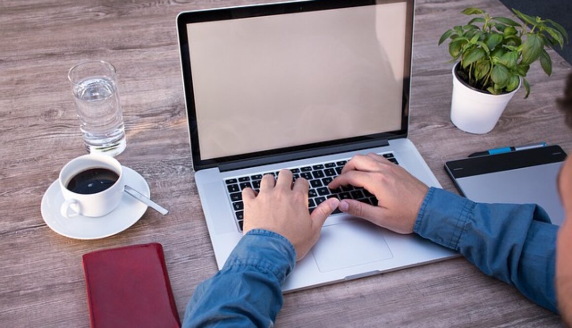 scrivania con computer, tazza di caffè, agenda, piantina