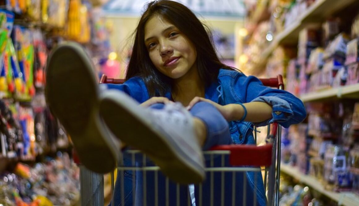 ragazza in un carrello tra corsie di supermercato