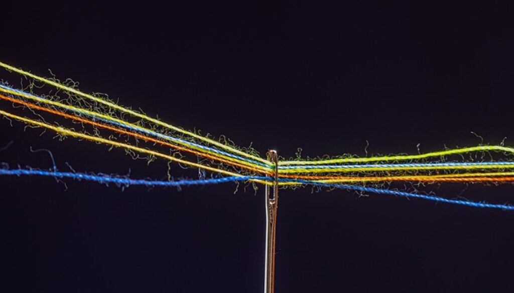 cruna di ago con fili colorati su sfondo nero