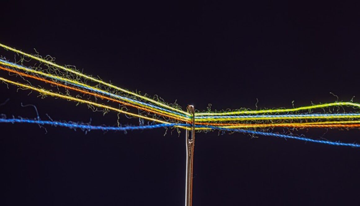 cruna di ago con fili colorati su sfondo nero