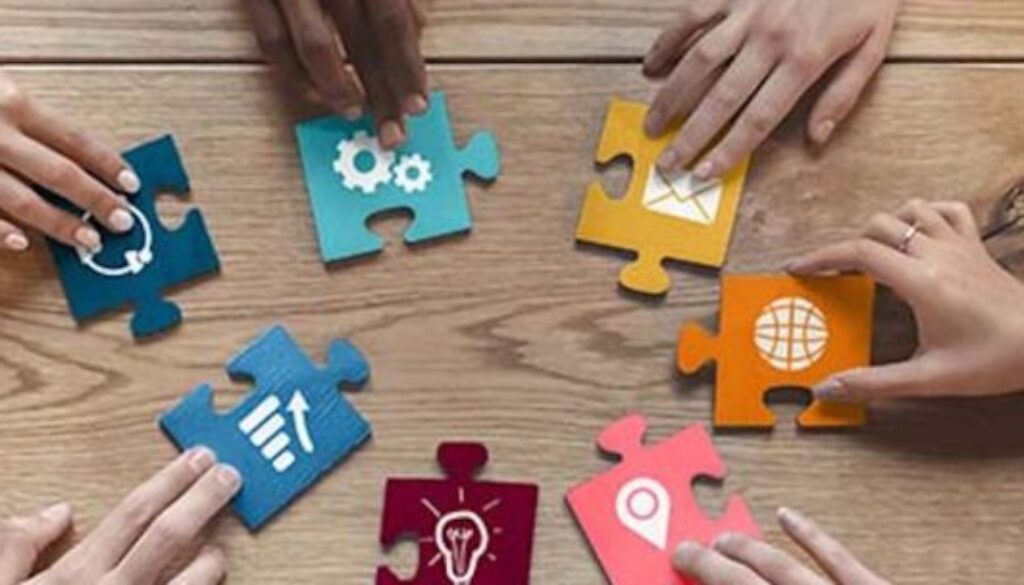 Hands of international coworkers putting colorful puzzles together