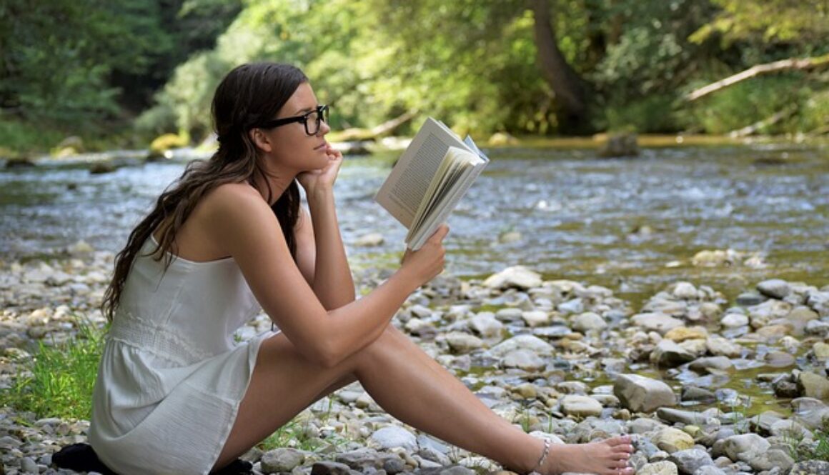 ragazza che legge sulla riva di un fiume