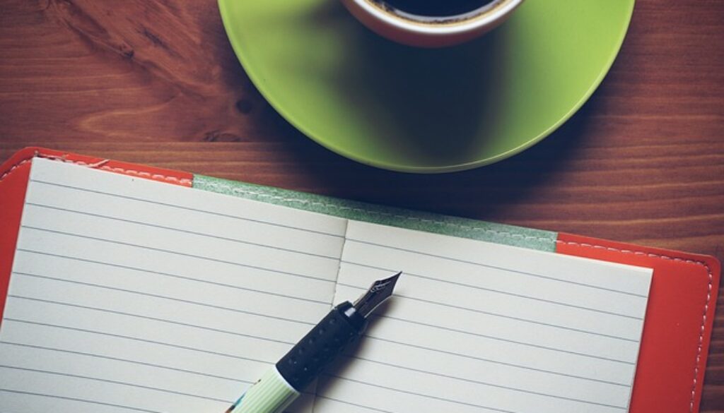 quaderno e penna stilografica con tazzina caffè